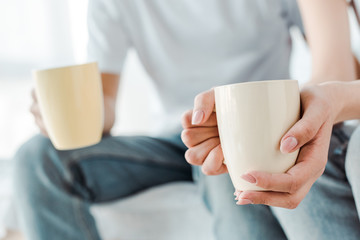 cropped view of couple holding cups of coffee