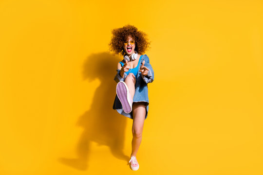 Full length body size photo funky funny she her lady wavy styling clubber strange moves fingers direct wear ear flaps specs casual jeans denim shirt shorts tank top clothes isolated yellow background