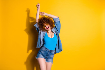 Close up photo beautiful she her lady wavy fluffy styling curls hand arm raised up sunny day wear specs casual jeans denim shirt shorts blue tank top outfit clothes isolated yellow bright background