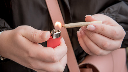 Marijuana joint in the female hand close-up. Woman smoking medical marijuana joint uotdoors.