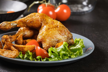 Roasted chicken legs with potato wedges and tomatoes