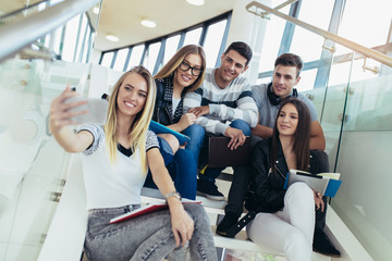 College life.Students are studying in library. Young people are spending time together. Reading book and communicating while sitting on stairs in library.