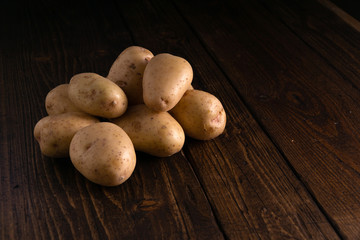 Heap of fresh clean potatoes on rustic wooden surface. Organic food, carbs, tubers.