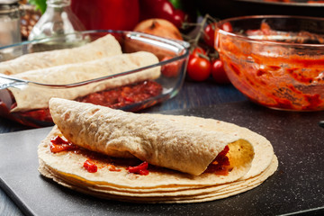 Preparation traditional mexican enchiladas with chicken meat, spicy tomato sauce and cheese