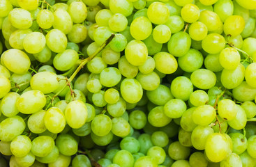 Green fresh grapes bunch lies in a wicker basket in the counter of a small market. 