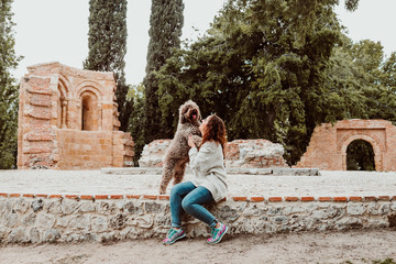 .Young and pretty woman spending free time with her nice brown spanish water dog in a park in the center of the city of Madrid. Lifestyle