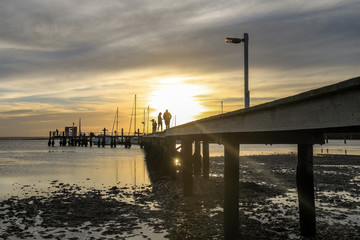 Fototapeta na wymiar Timber jetty leading to sunset with silhouettes