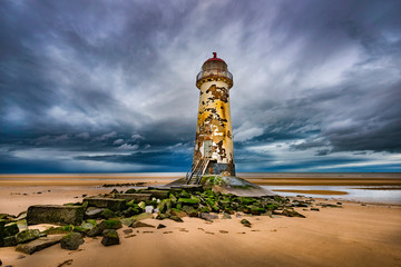 Desrted winter beach with threatening sky and decrepit lighthouse