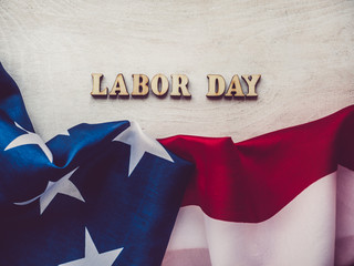 Fototapeta na wymiar LABOR DAY. American flag and wooden letters of the alphabet on a white table. Close-up, top view. Bright photo with space for your inscriptions. Congratulations to relatives, friends and colleagues
