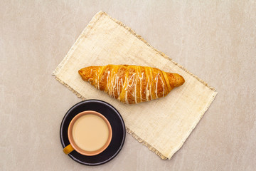 A cup of fresh coffee with croissant. The concept on a stone background, vintage linen napkin, top view, flat lay, close up.