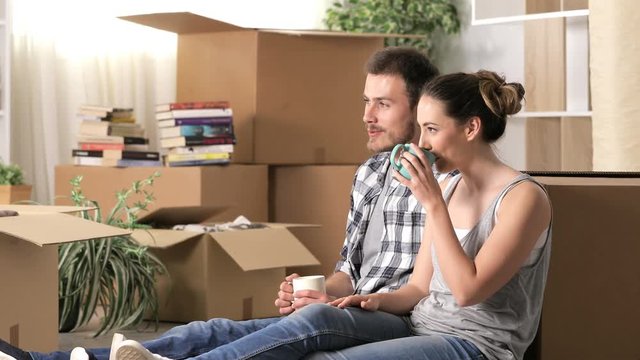 Happy couple moving home resting and talking sitting on the floor