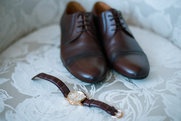 The groom is gathering in the morning. A gray chair. Men's Black classic patent leather shoes. A...