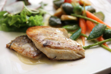 Sea bass fillet with grilled vegetables and salad on wooden table