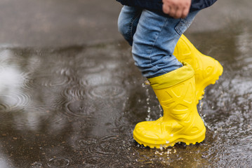 little boy walks through the puddles in the spring after the rain