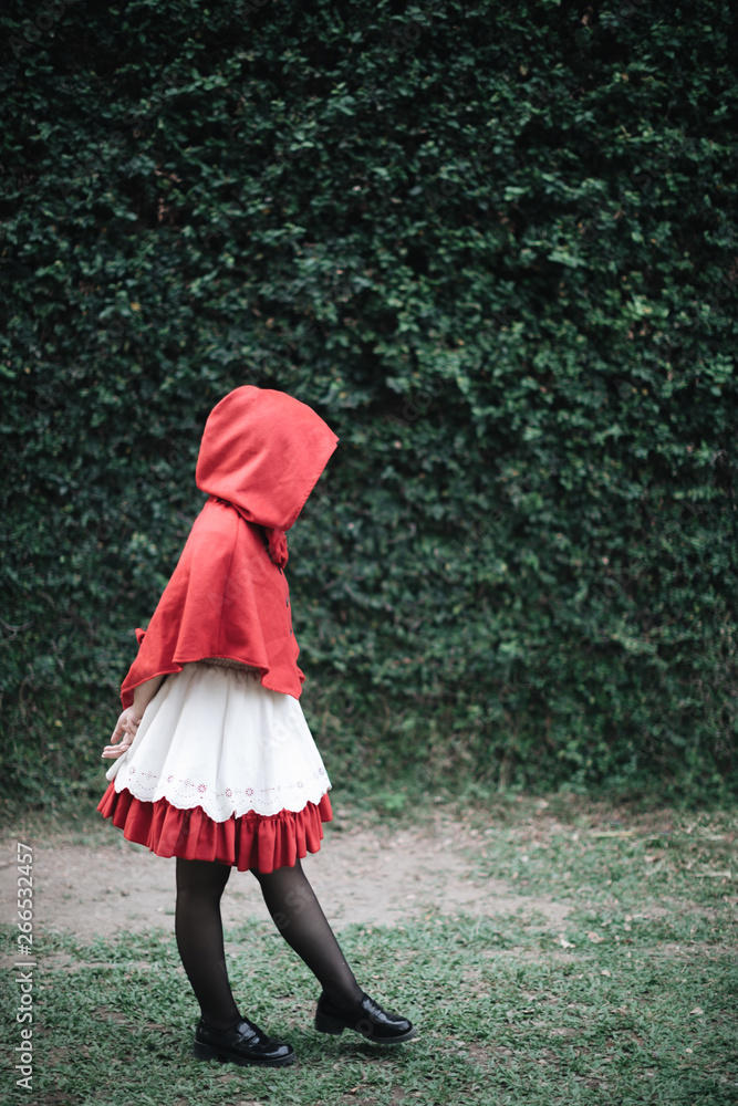 Wall mural portrait young woman with little red riding hood costume in green tree park