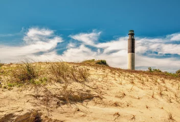 Wandcirkels aluminium A beautiful lighthouse landscape over sand dunes and a cloudy blue sky in high definition. © Mark Alan Howard