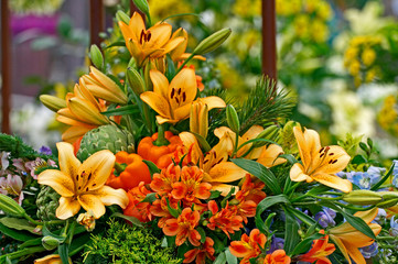 A colourful and attractive flower arrangement of orange flowers and peppers