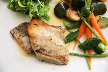 Sea bass fillet with grilled vegetables and salad on wooden table