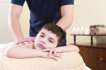 Fototapeta na wymiar Relaxed little boy on reception at the chiropractor. Wellness massage procedure