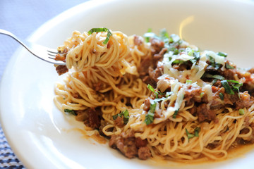 spaghetti Bolognese with minced beef and tomato sauce garnished with parmesan cheese and basil , Italian food