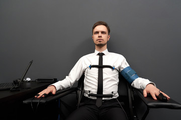Man sitting with attaching sensors on fingers and  body.