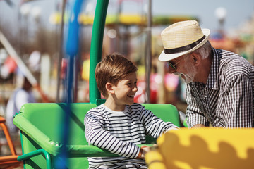 Grandfather and grandson having fun and spending good quality time together in amusement park.