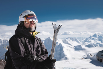 Portrait athlete skier in helmet and ski mask against the snow-capped mountains of a ski resort...