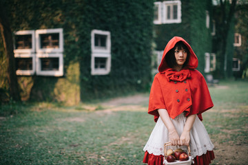 Portrait young woman with Little Red Riding Hood costume in green tree park