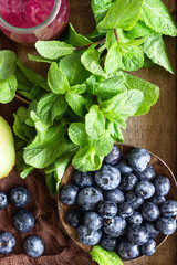 Purple smoothie with fresh blueberries, mint, avocado and grapefruit in wooden tray. Healthy food. Clear eating selection. Summer breakfast or lunch.
