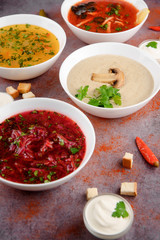 Set of soups from worldwide cuisines, healthy food. Cream soup with mushrooms,solyanka, russian borscht, chicken soup on silver background. Top view.