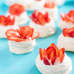 Beautiful pavlova cakes with strawberries on a blue background. Selective focus. Tasty sweet breackfast. Wedding morning. Meringue with cream.