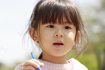 シャボン玉で遊ぶ幼児(4歳児)と青空