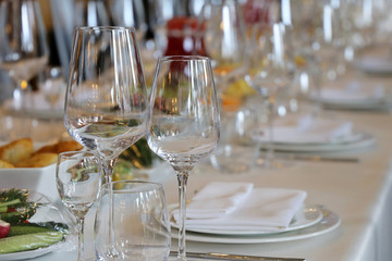 Banquet and catering, table set in the restaurant for celebration. Empty glasses, snacks and plates with napkins on the desk