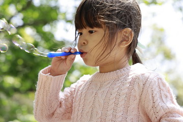 シャボン玉で遊ぶ幼児(4歳児)と青空