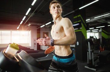 Fototapeta na wymiar Man running in a modern gym on a treadmill concept for exercising, fitness and healthy lifestyle and listening music