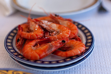 A narrow depth of field image of a plate of cooked and salted prawns served in a restaurant