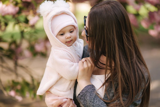 Portrait of mother and her little baby girl. Beautiful mom and cute baby. Mother hud her daughter. Baby dressed in peanch colour hat and smile