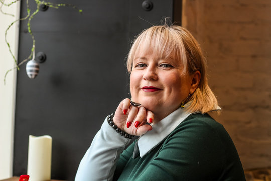 A thick blond woman works in a cafe. A business woman writes in a notebook. Work freelancer.