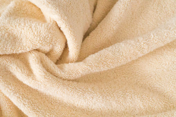 Fluffy beige towel background, close-up. Gentle baby pastel fabric with waves and folds. Folded...