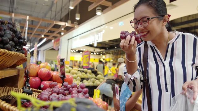 Happy woman buying fresh fruit in convenience store