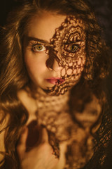 Passionate eyes glance. Emotional expressive portrait of a beautiful girl with lace shadows on her face