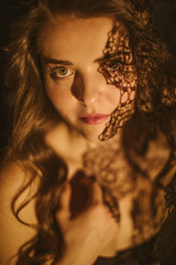 Sensitive sexy portrait of a girl with a lacy shadow on her face. Feminine and sexy. Mysterious atmospheric twilight. Warm sepia colors. Summer night passion