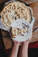Woman holding a freshly baked piece of cheesecake. View from directly from above