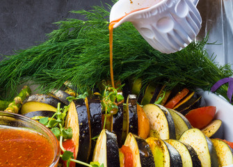 Ratatouille - traditional French Provencal vegetable dish cooked in oven pouring with tomato, olive...