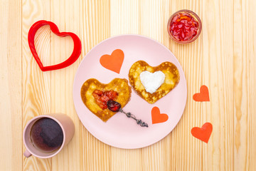 Fototapeta na wymiar Heart shaped pancakes for romantic breakfast with strawberry jam and black tea. Shrovetide (carnival) concept. On wooden background, top view