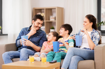 Obraz na płótnie Canvas family, leisure and people concept - happy mother, father, son and daughter with popcorn watching tv at home