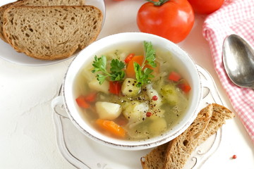Fresh vegetable soup from potatoes, carrots, cabbage, sweet pepper, brussels sprouts in a bowl with parsley top view