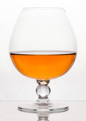 side view of crystal glass with brown cognac on white background with copy space