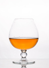 side view of transparent glass on stem with brown drink on white background with copy space