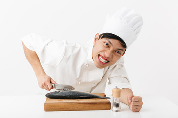 Image of young japanese chief man in white cook uniform cooking and fillet raw fresh fish with knife